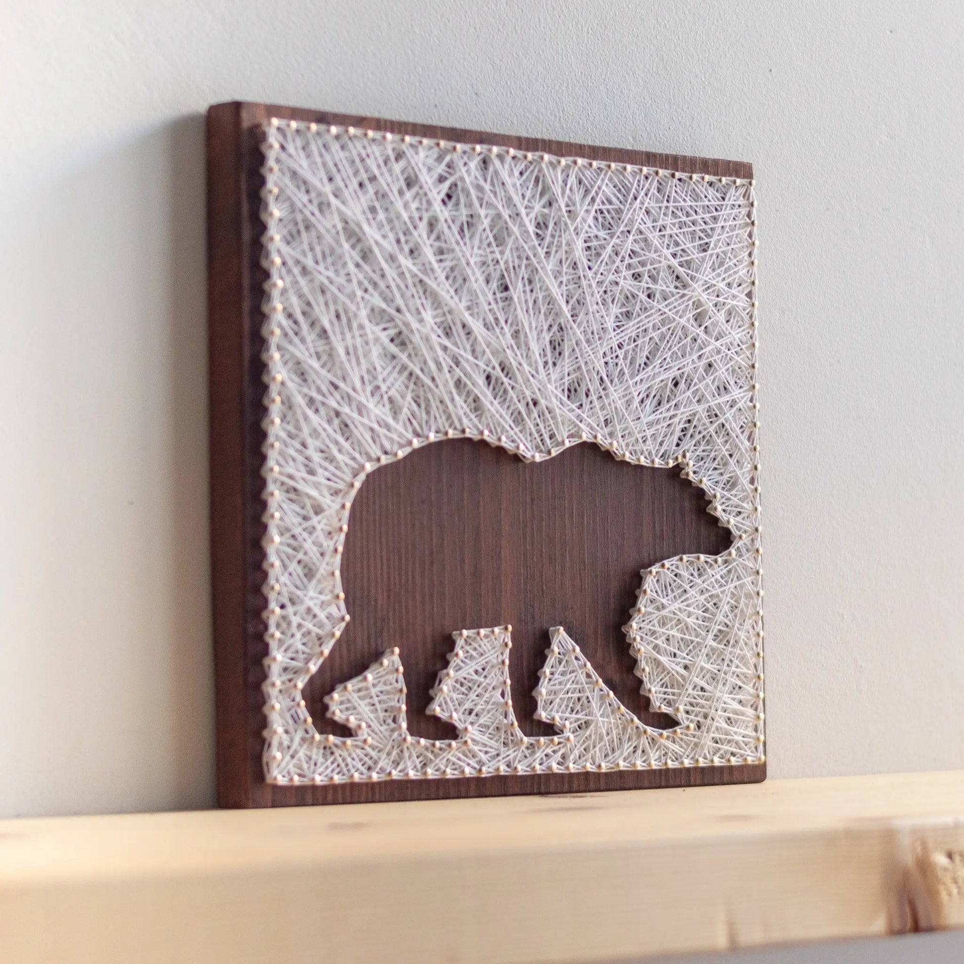 DIY string art kit featuring a bear silhouette with white threads on a dark wooden board by GoodStrings