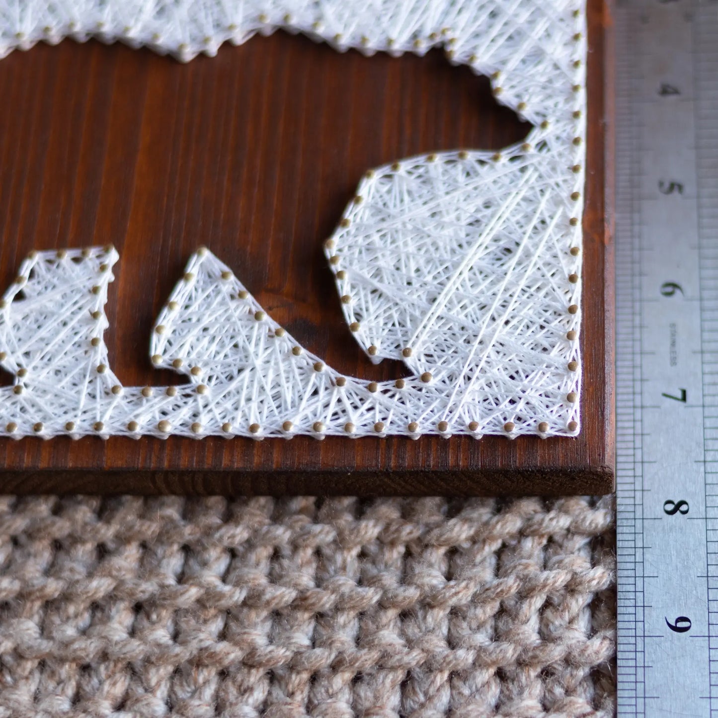 DIY string art kit featuring a bear silhouette with white threads on a dark wooden board by GoodStrings