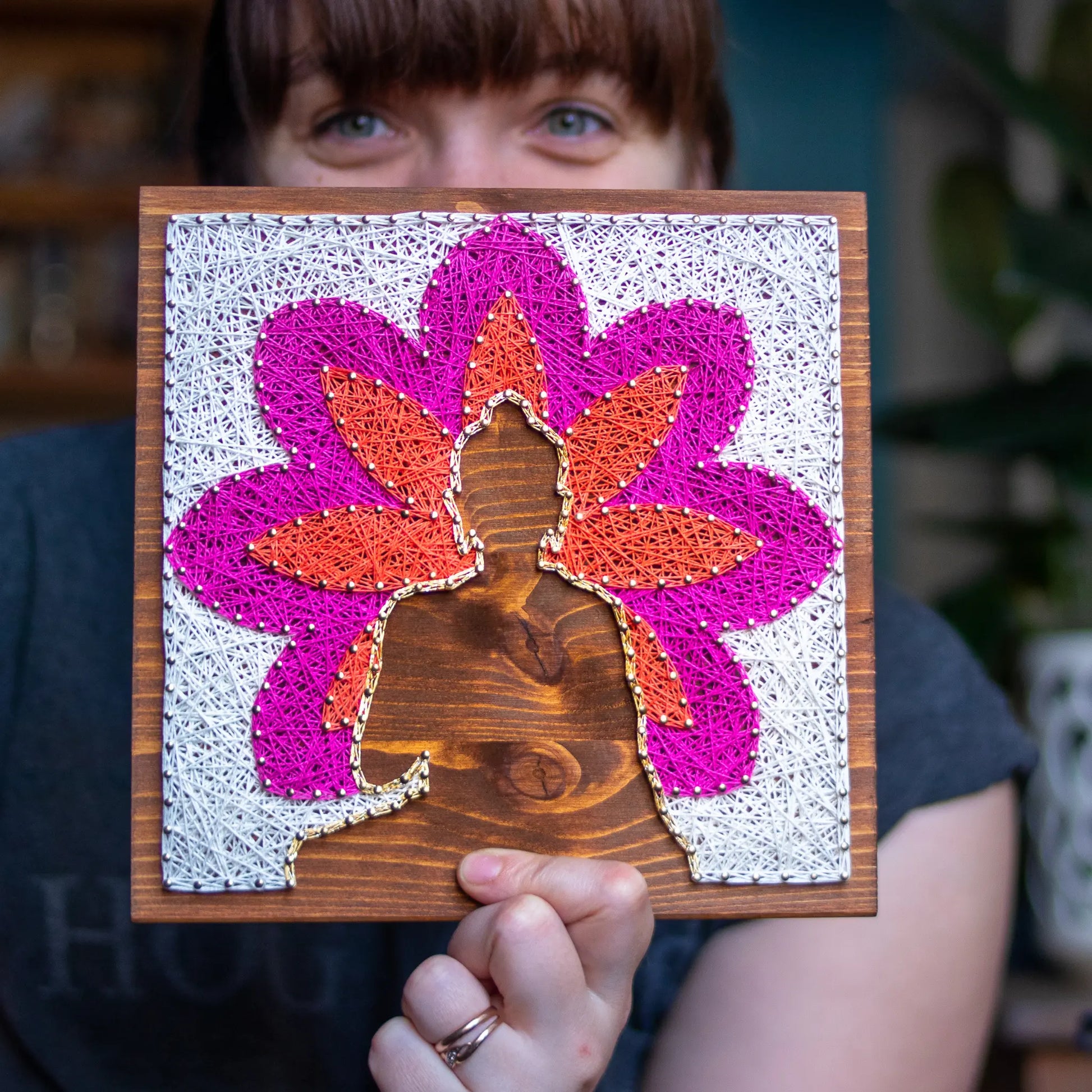 DIY string art kit featuring a Buddha silhouette surrounded by a colorful flower pattern on a wooden board by GoodStrings