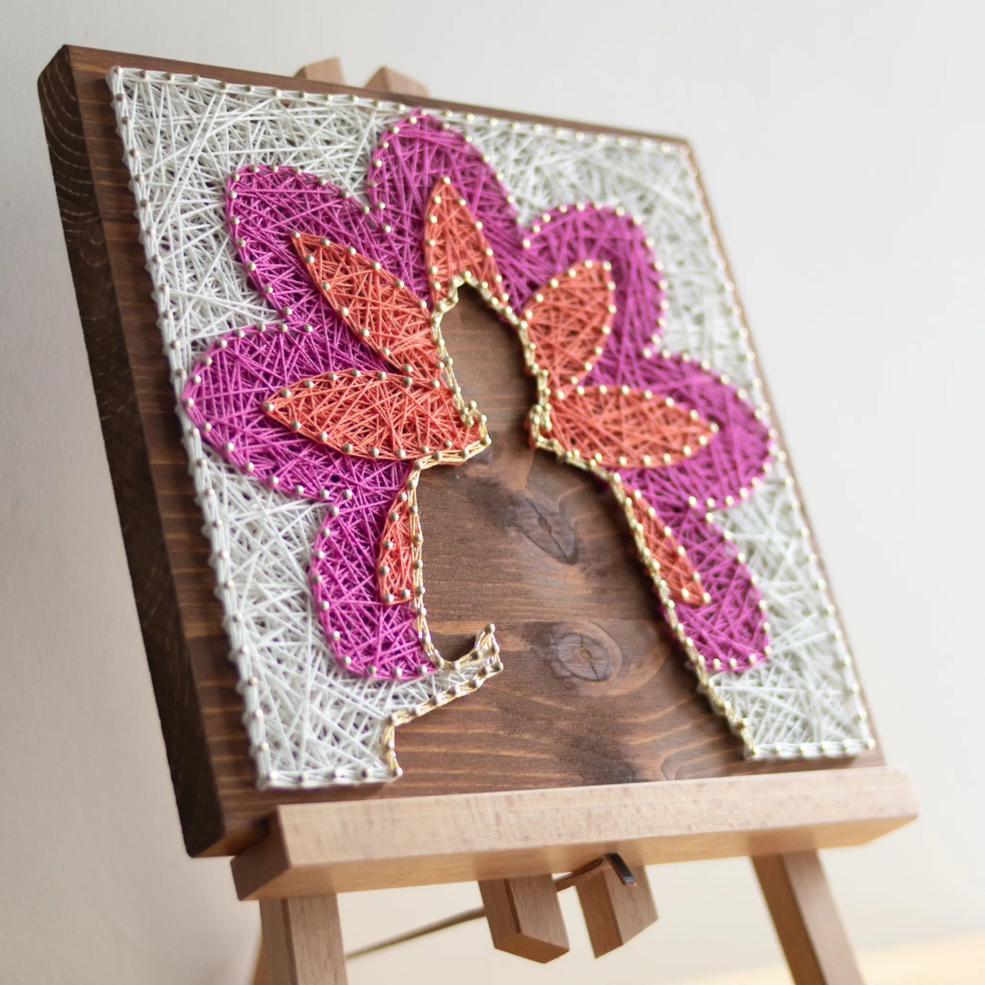 DIY string art kit featuring a Buddha silhouette surrounded by a colorful flower pattern on a wooden board by GoodStrings