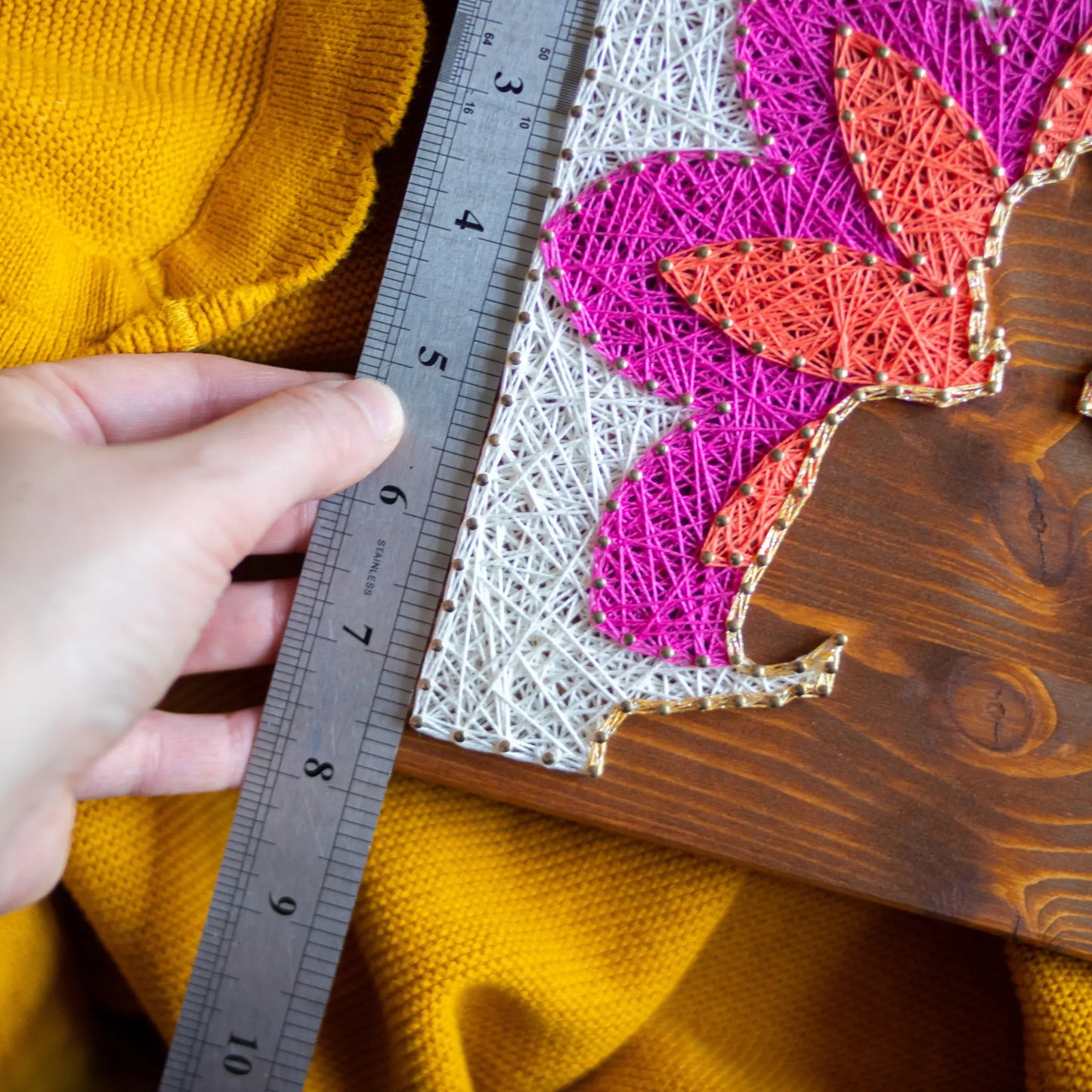 DIY string art kit featuring a Buddha silhouette surrounded by a colorful flower pattern on a wooden board by GoodStrings