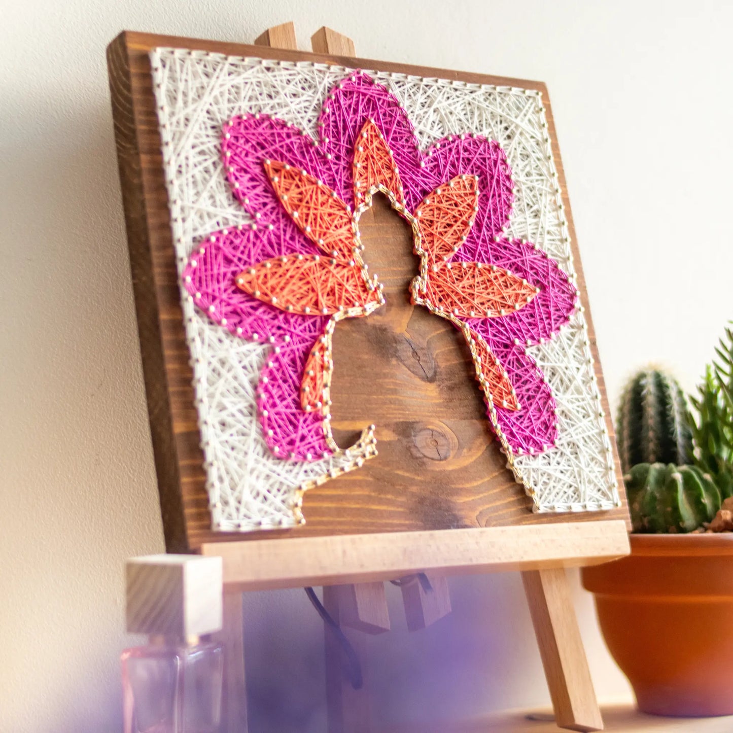 DIY string art kit featuring a Buddha silhouette surrounded by a colorful flower pattern on a wooden board by GoodStrings