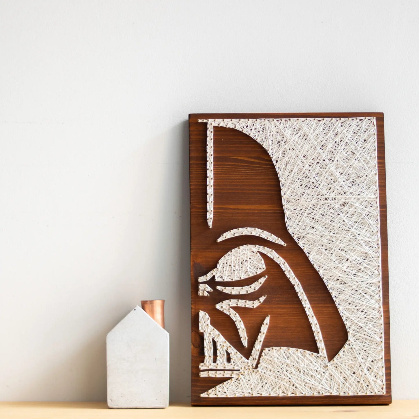 DIY string art kit featuring a silhouette of Darth Vader outlined with white thread on a rustic wooden board by GoodStrings - front view