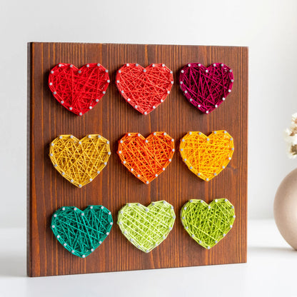 DIY string art kit with colorful hearts on a rustic wooden board by GoodStrings front view