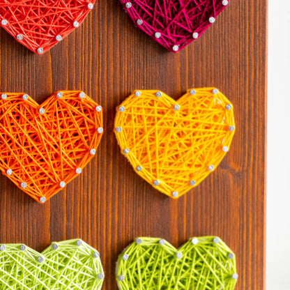 DIY string art kit with colorful hearts on a rustic wooden board by GoodStrings