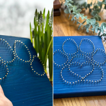  charming dog paw print string art sign made with white and dark brown string on a blue wooden background, featuring a heart shape in the center of the paw print in process 