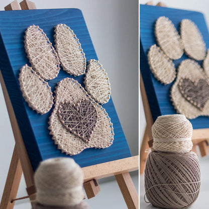  charming dog paw print string art sign made with white and dark brown string on a blue wooden background, featuring a heart shape in the center of the paw print.