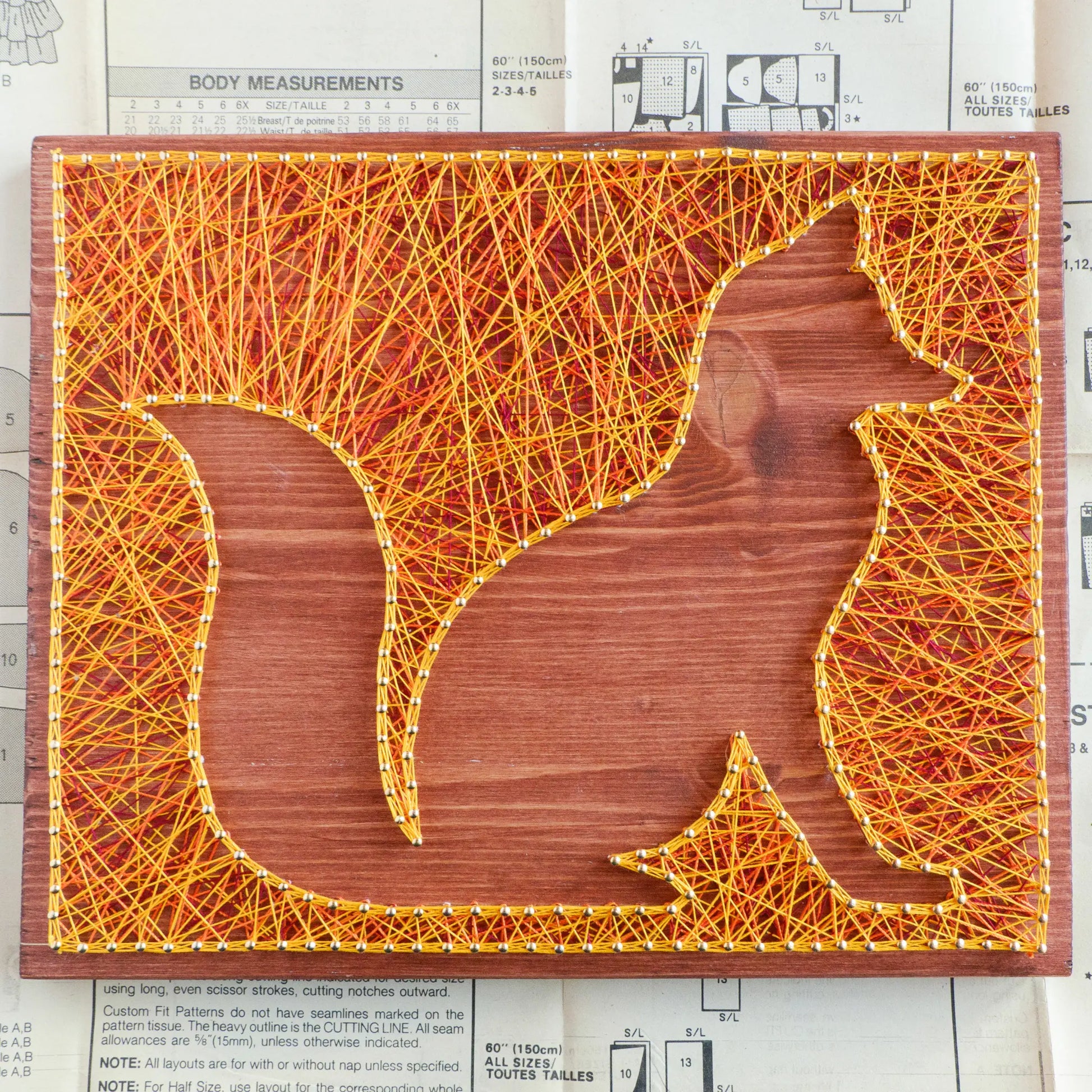 Orange and yellow fox string art on a wooden board from Goodstrings DIY kits for adults.