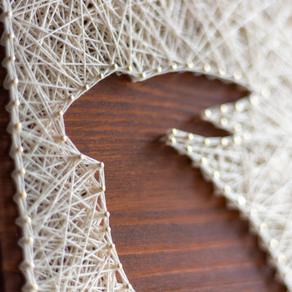 A charming rabbit string art sign made with white string on a dark wooden background, depicting a sitting rabbit silhouette.