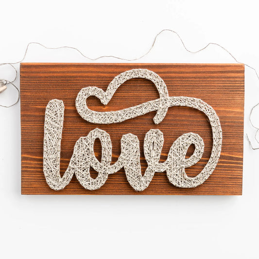 DIY string art kit spelling 'love' on a rustic wooden board by GoodStrings