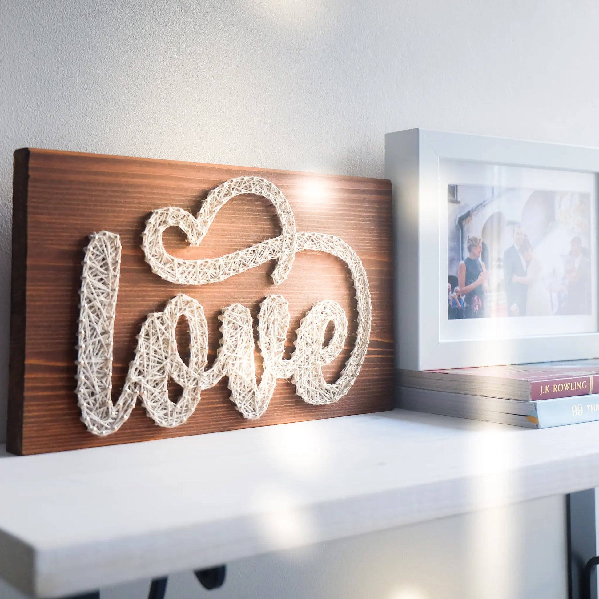 DIY string art kit spelling 'love' on a rustic wooden board by GoodStrings