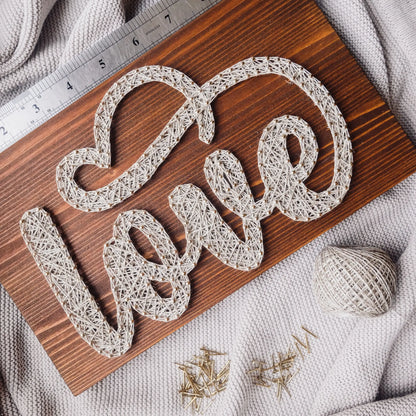 DIY string art kit spelling 'love' on a rustic wooden board by GoodStrings