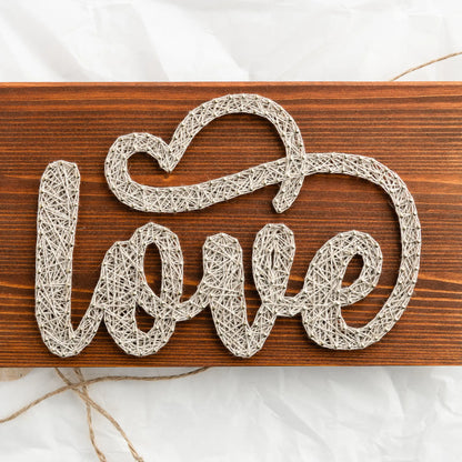 DIY string art kit spelling 'love' on a rustic wooden board by GoodStrings