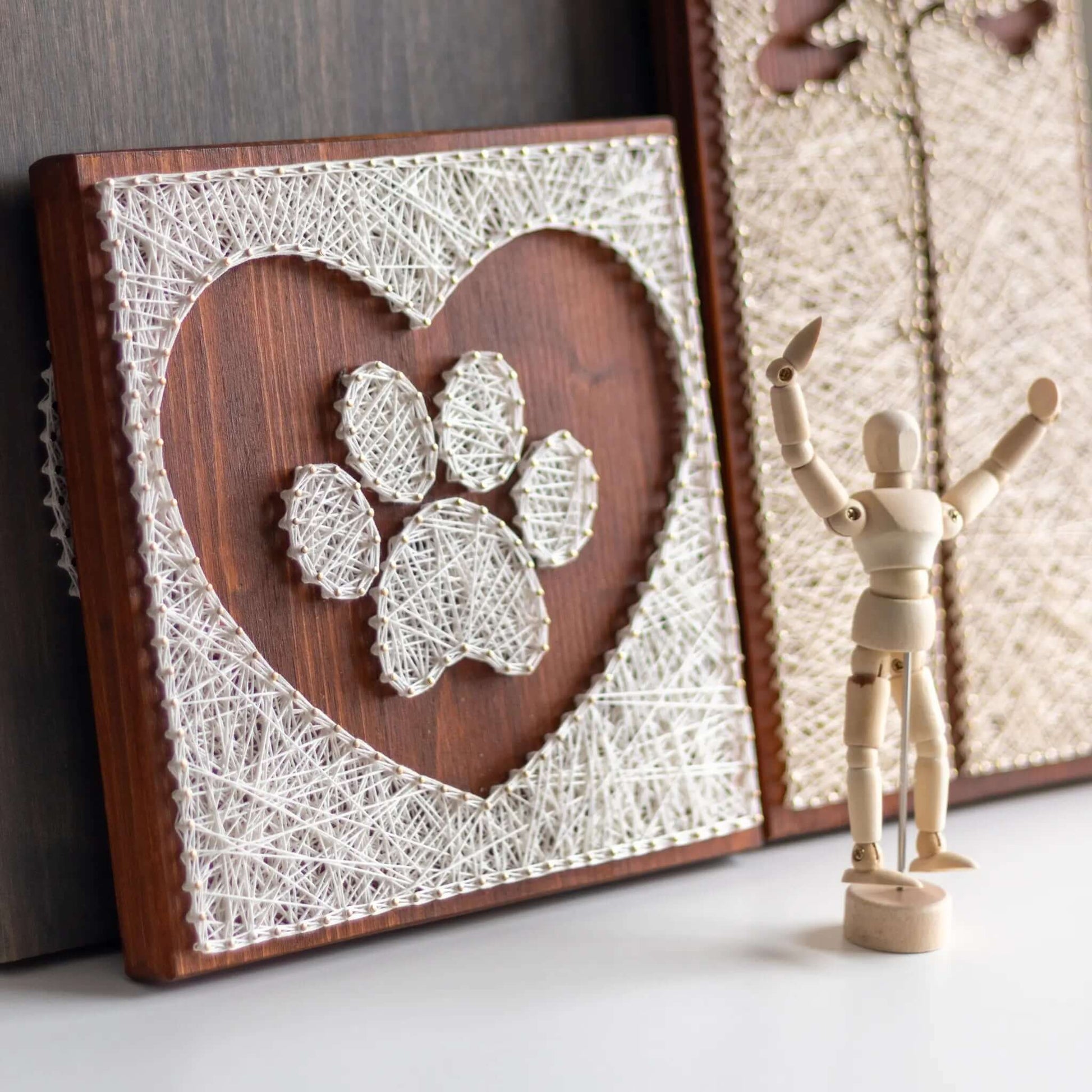 dog paw in a heart string art craft kit on a brown wood base made with gold color nails