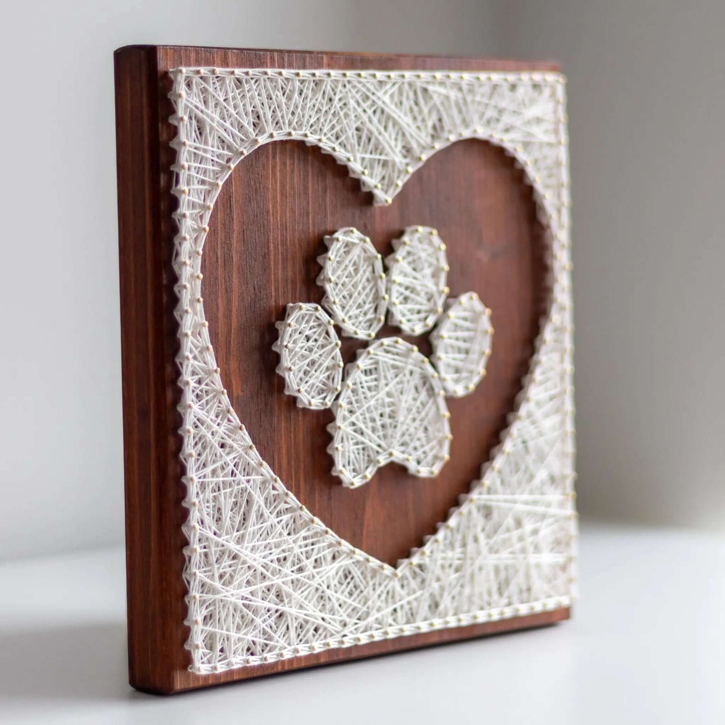 dog paw in a heart string art craft kit on a brown wood base made with gold color nails