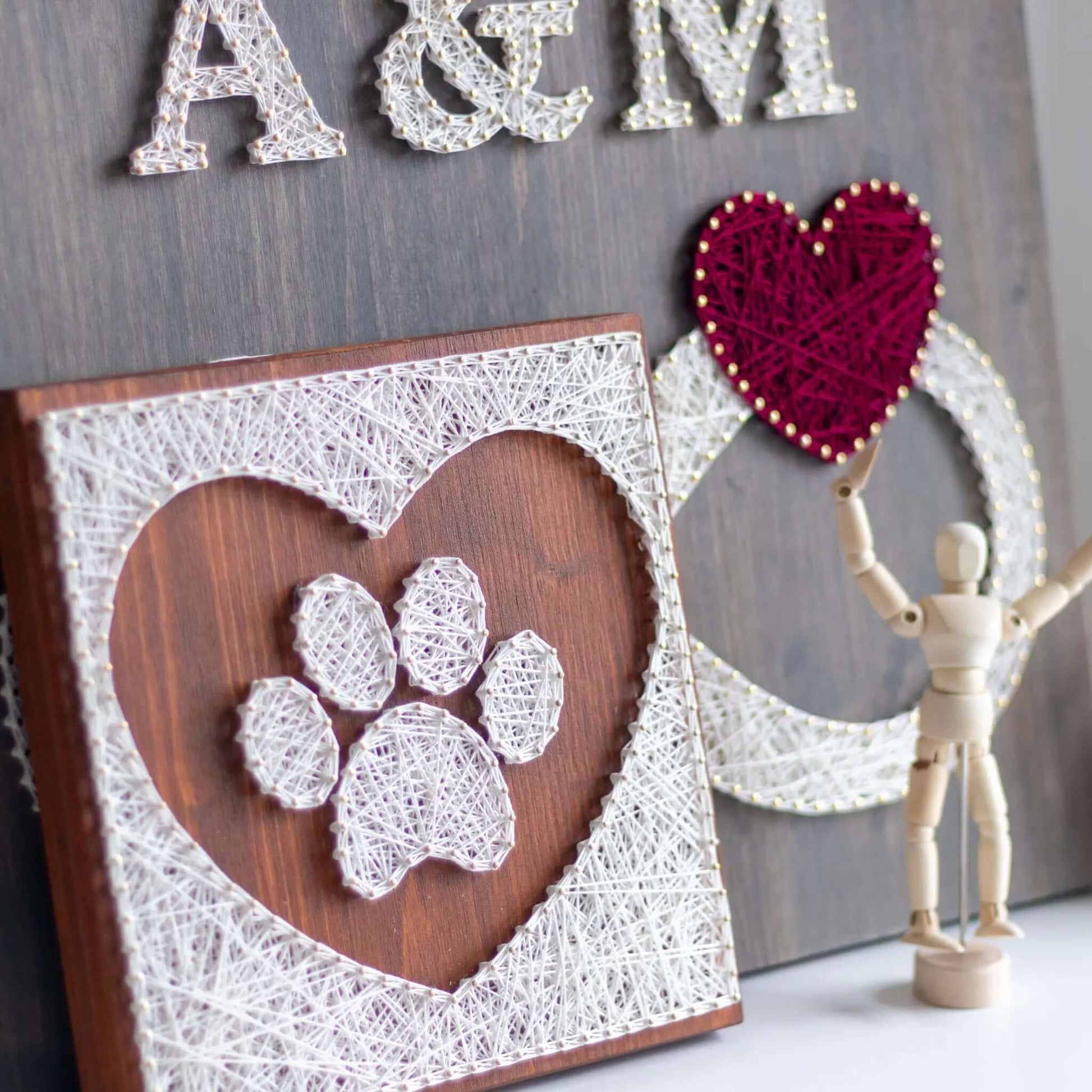 dog paw in a heart string art craft kit on a brown wood base made with gold color nails