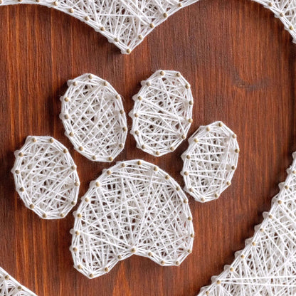 dog paw in a heart string art craft kit on a brown wood base made with gold color nails