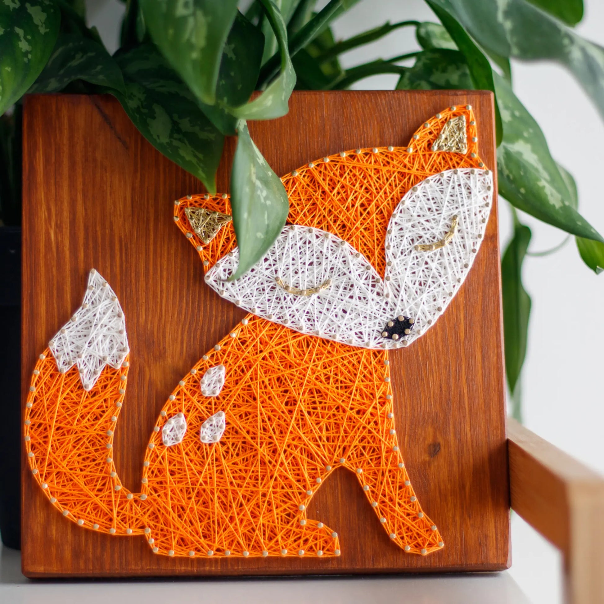 DIY string art kit featuring a cute fox silhouette with orange and white threads on a rustic wooden board by GoodStrings