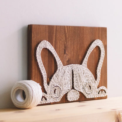 DIY string art kit featuring a cute French Bulldog silhouette outlined with ivory thread on a rustic wooden board by GoodStrings - on shelf, from side