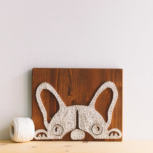 DIY string art kit featuring a cute French Bulldog silhouette outlined with ivory thread on a rustic wooden board by GoodStrings - on shelf, front view