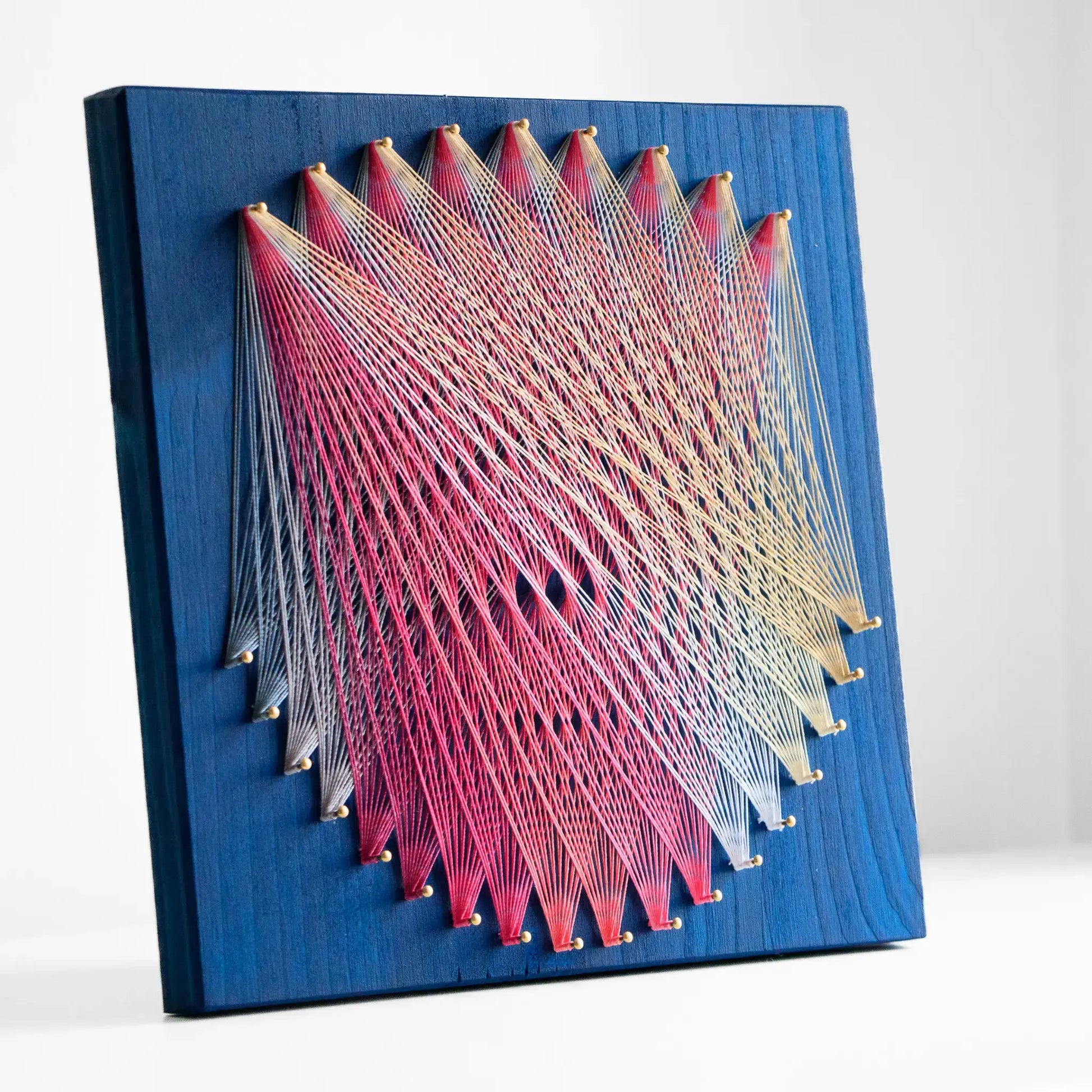 Geometric string art with pink and grey threads on blue base, ideal craft kit for adults, featuring detailed pattern - grey and pink