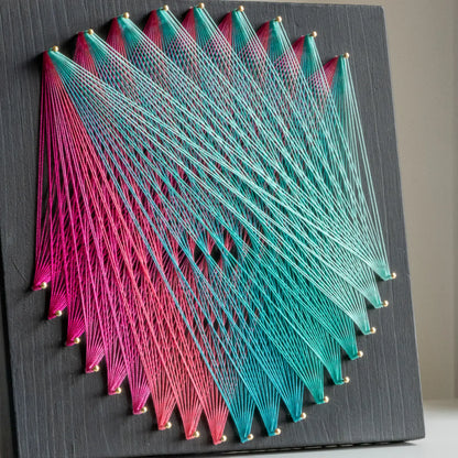 Geometric string art with pink and teal threads on black base, part of craft kits for adults, highlighting intricate design.DIY geometric string art kit featuring a vibrant mandala design with multiple color options on a black wooden board by GoodStrings - pink and teal