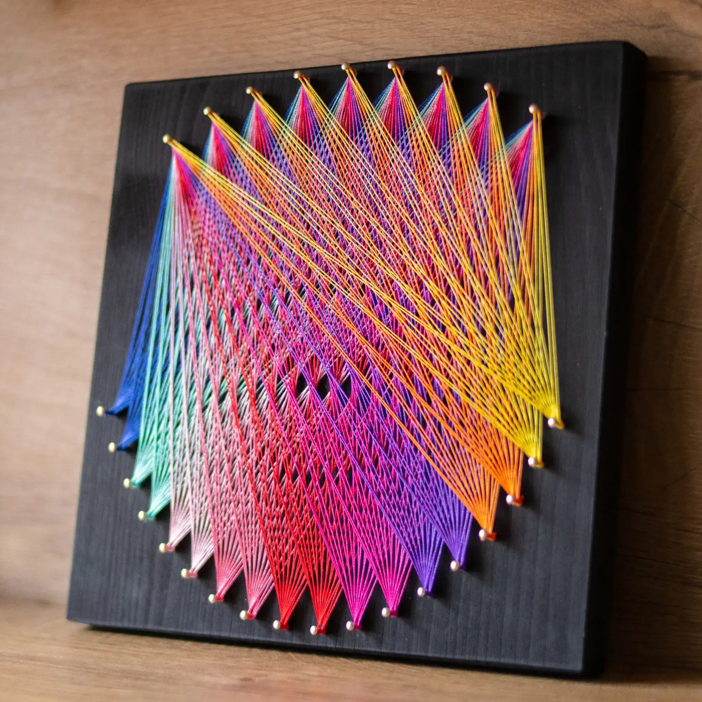 Geometric string art with rainbow threads on black base, ideal craft kit for adults, featuring detailed pattern - rainbow pride colors