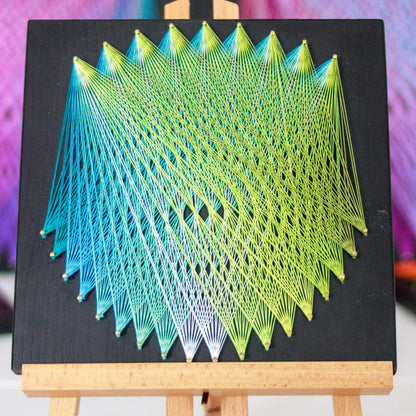 Geometric string art with blue and green threads on black base, perfect craft kit for adults, showcasing detailed pattern on easel - green and blue