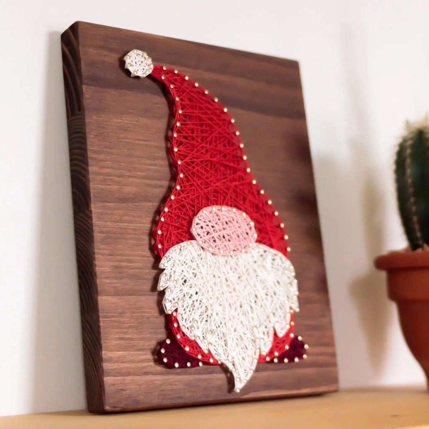 DIY string art kit featuring a gnome with a red hat and white beard, created with colorful threads on a wooden board by GoodStrings