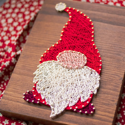 DIY string art kit featuring a gnome with a red hat and white beard, created with colorful threads on a wooden board by GoodStrings