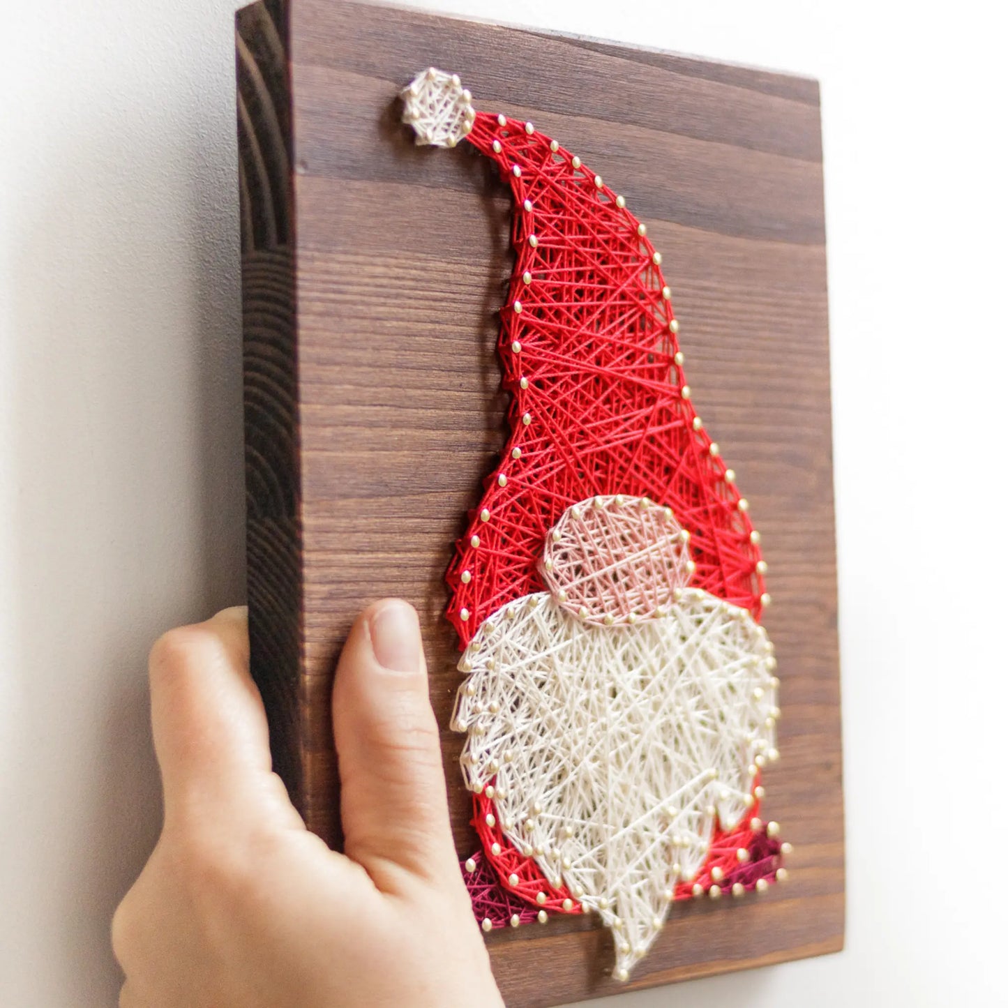 DIY string art kit featuring a gnome with a red hat and white beard, created with colorful threads on a wooden board by GoodStrings