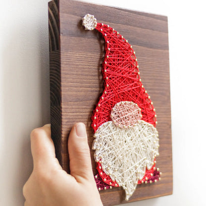 DIY string art kit featuring a gnome with a red hat and white beard, created with colorful threads on a wooden board by GoodStrings