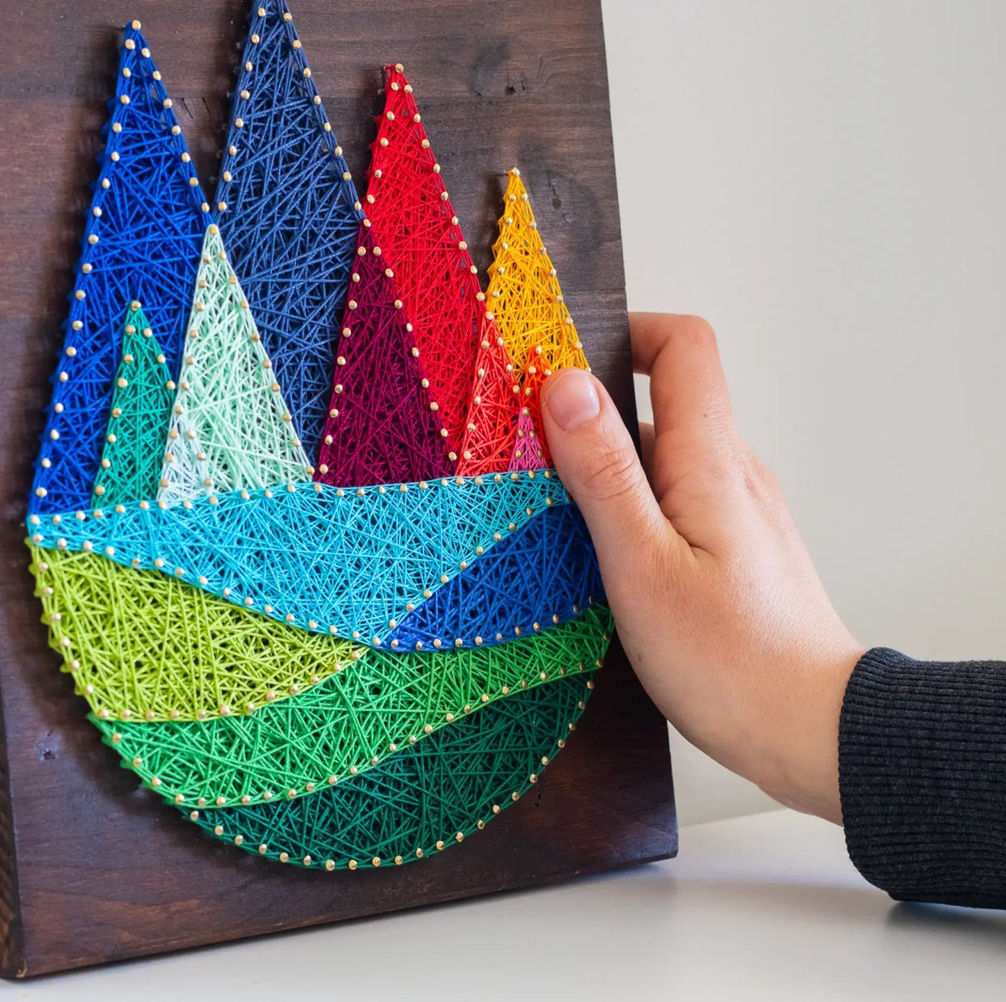 DIY string art kit featuring colorful mountains created with vibrant threads on a dark wooden board by GoodStrings