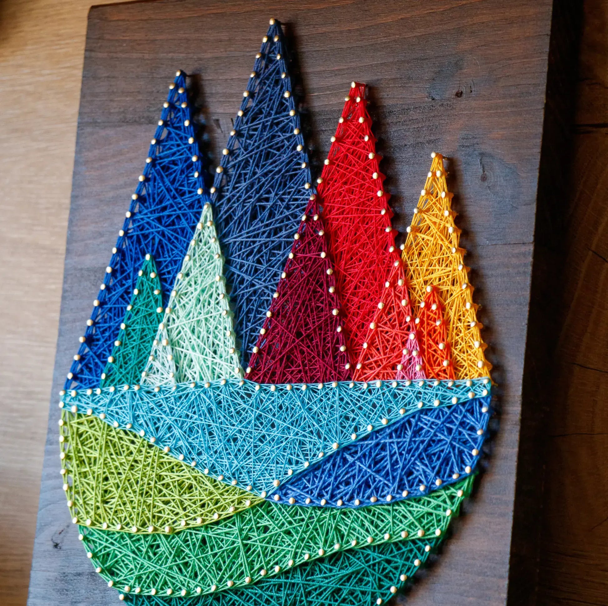 DIY string art kit featuring colorful mountains created with vibrant threads on a dark wooden board by GoodStrings