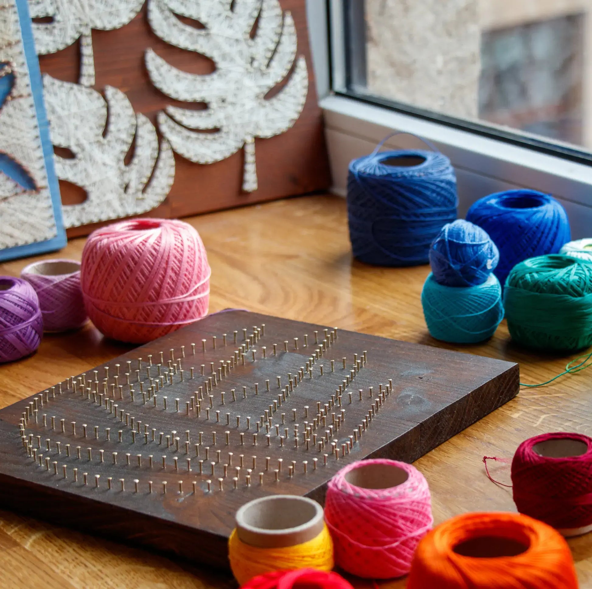 DIY string art kit featuring colorful mountains created with vibrant threads on a dark wooden board by GoodStrings