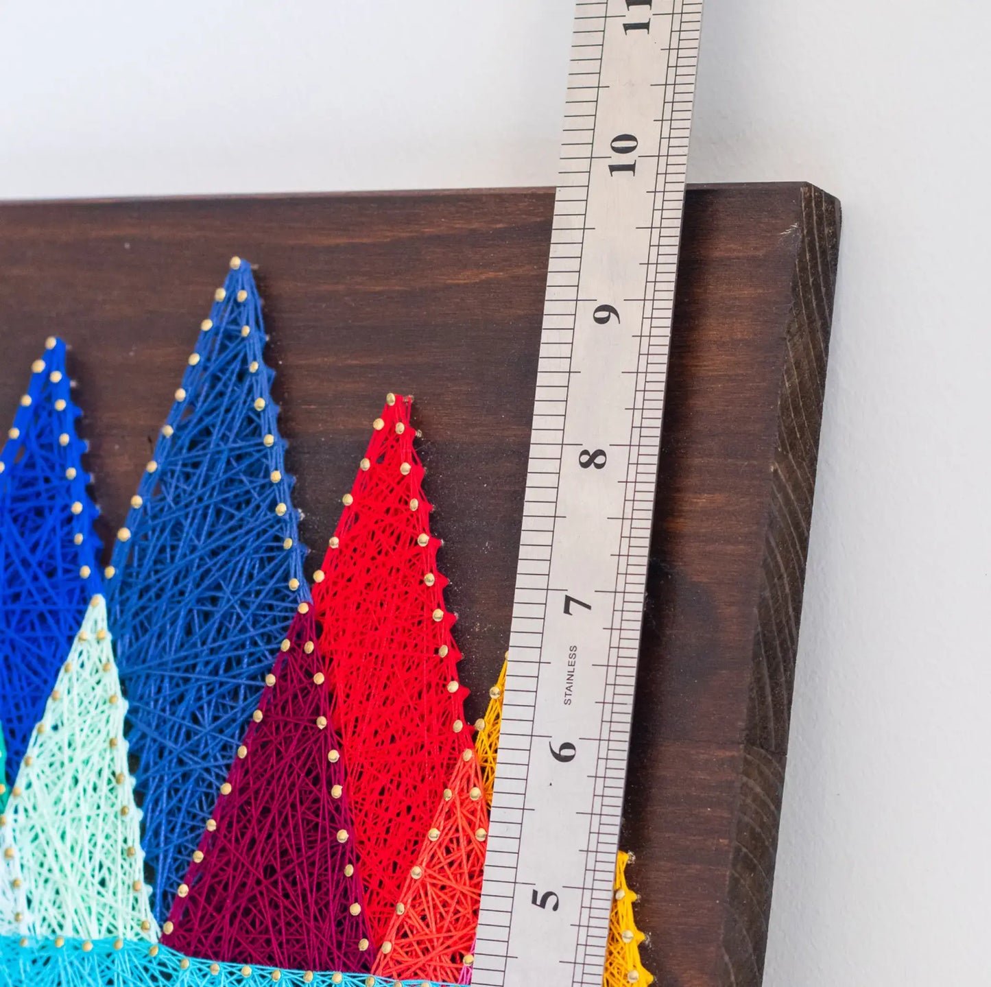 DIY string art kit featuring colorful mountains created with vibrant threads on a dark wooden board by GoodStrings