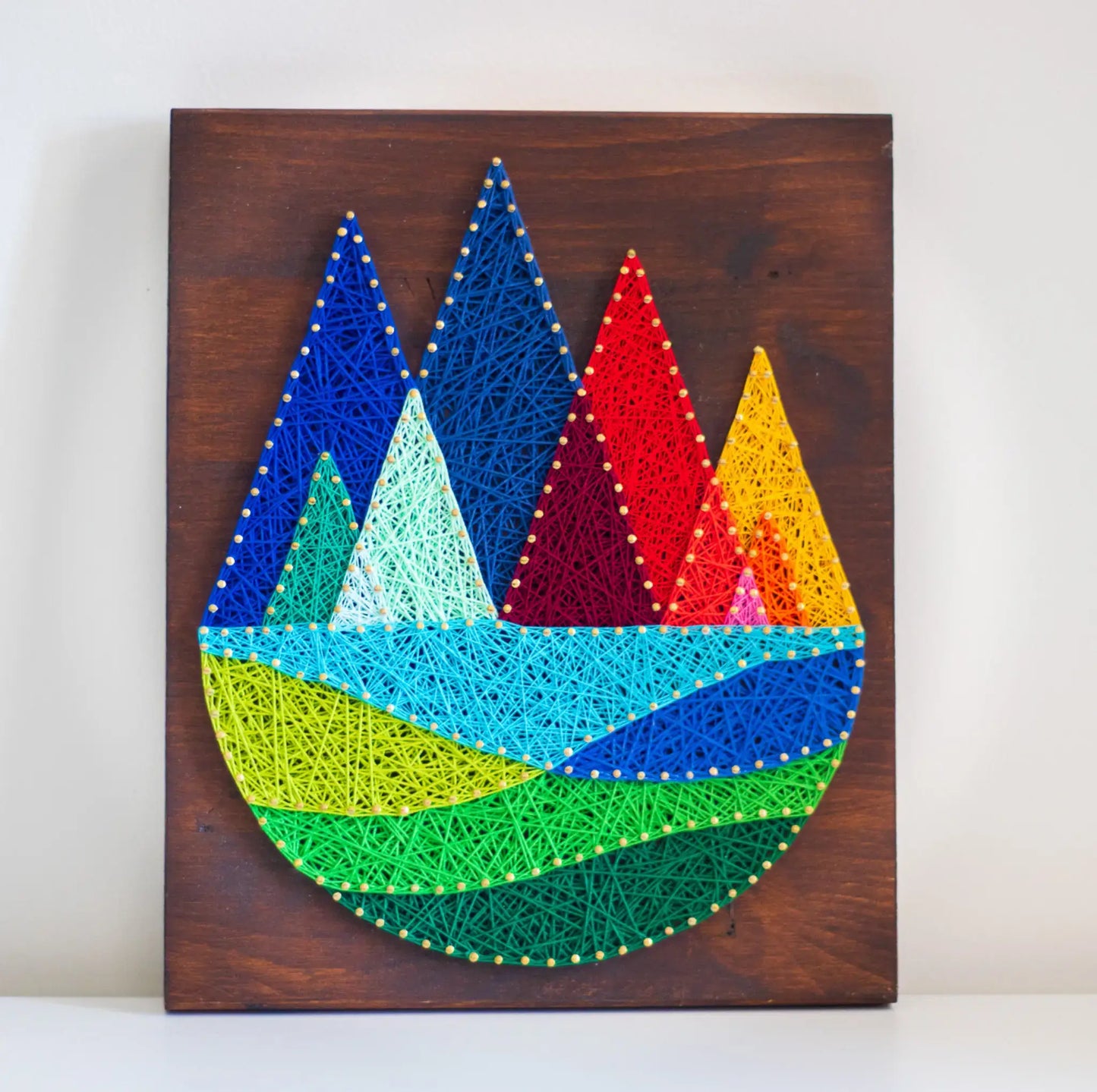 DIY string art kit featuring colorful mountains created with vibrant threads on a dark wooden board by GoodStrings