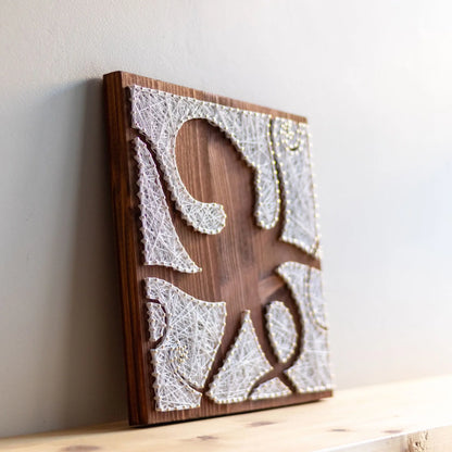 DIY string art kit featuring an octopus silhouette with various geometric shapes created with white threads on a dark wooden board by GoodStrings