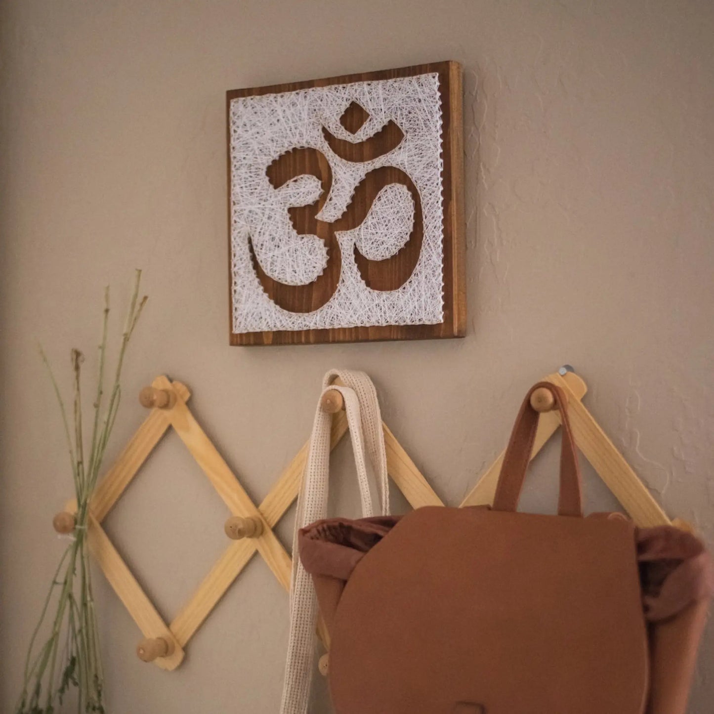 DIY string art kit featuring an Om symbol outlined with white thread on a rustic wooden board by GoodStrings - lifestyle picture