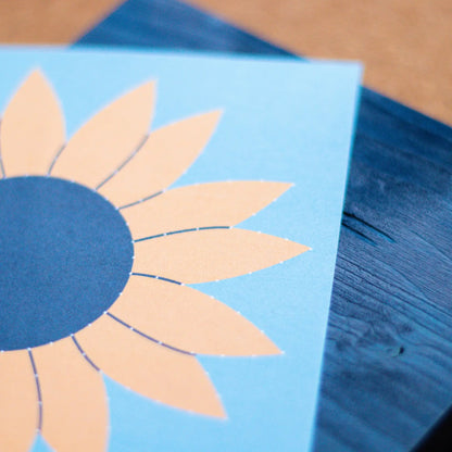 DIY string art kit featuring a bright yellow sunflower with a brown center created with threads on a dark blue wooden board by GoodStrings