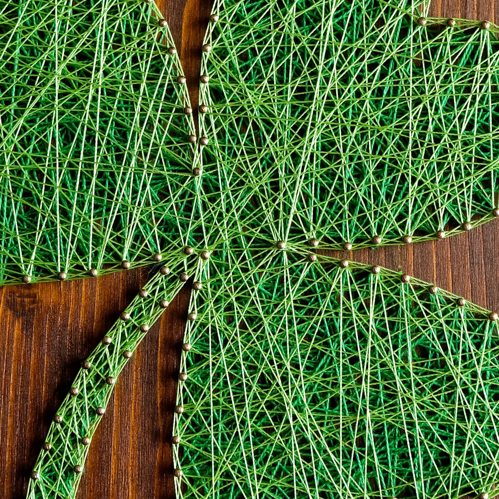 DIY string art kit featuring a three-leaf clover outlined with green thread on a rustic wooden board by GoodStrings - string layers shot