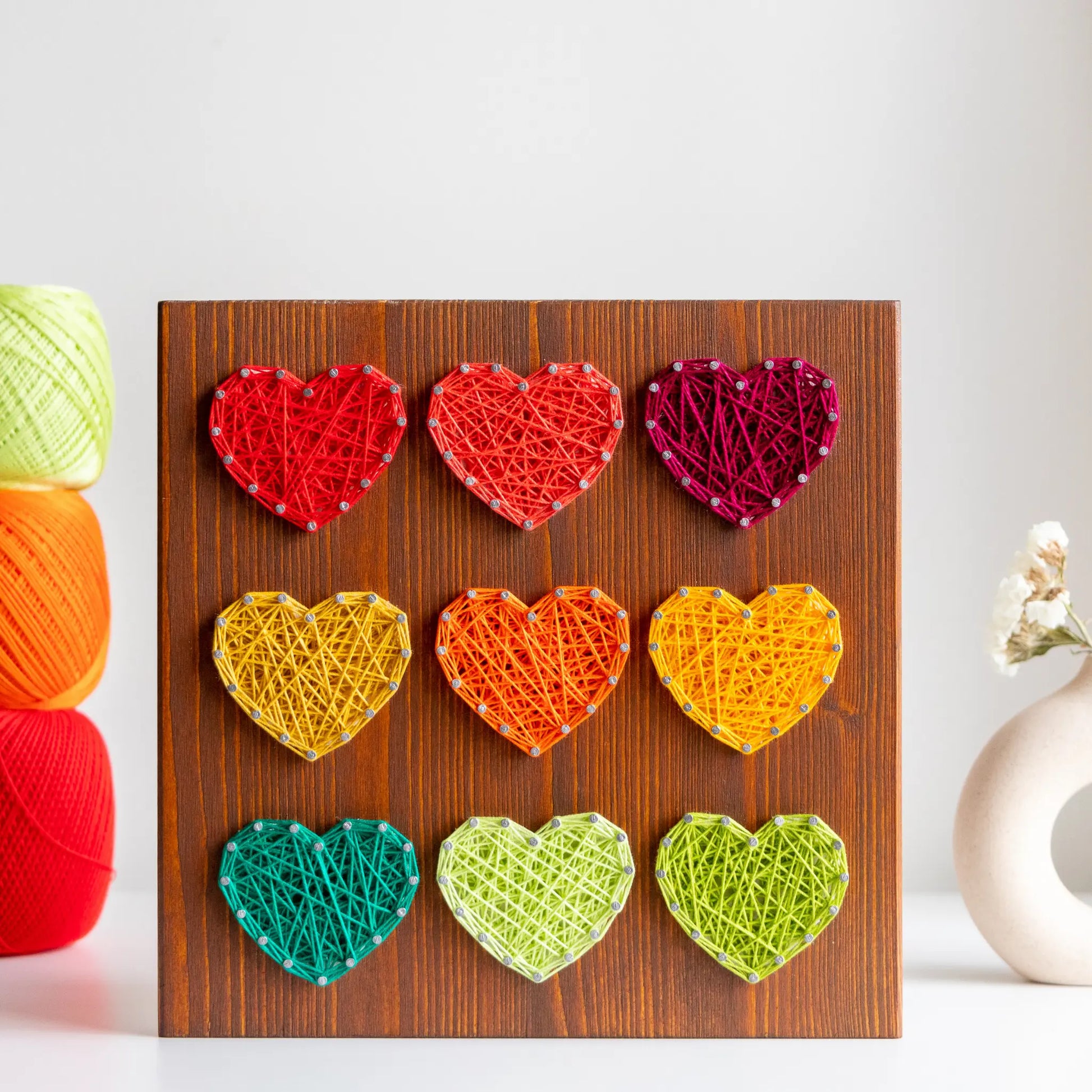 Front view. Heart string art pattern design on a wooden board featuring multiple heart shapes. A DIY craft project, perfect for home decor, made using nails and string. Available as a digital download for easy crafting.