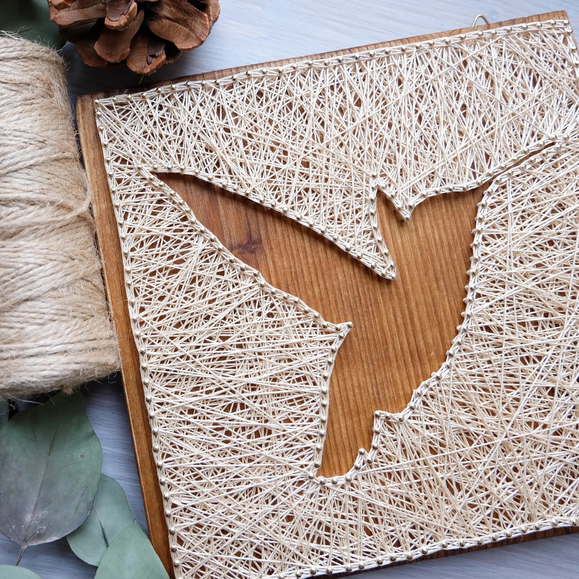 Sign created using a GoodStrings hummingbird sting art pattern. Elegant ivory thread design on a wooden board, perfect for adding a touch of nature to any room.