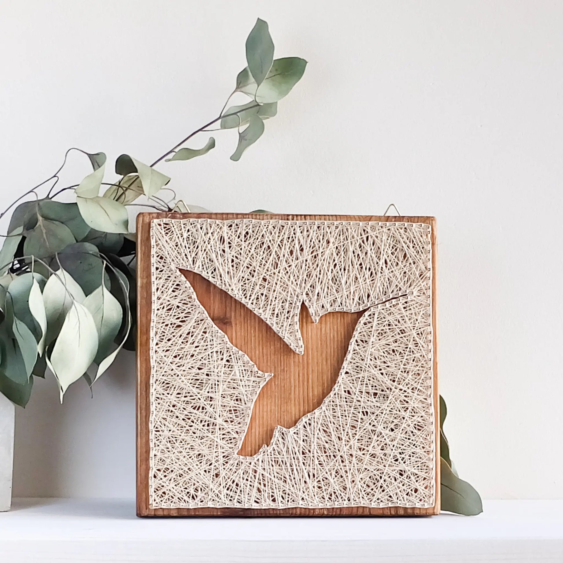 Nature-inspired string art design on a wooden base, crafted using GoodStrings' downloadable hummingbird string art pattern for beginners.