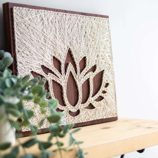 lotus string art sign on a brown wood base