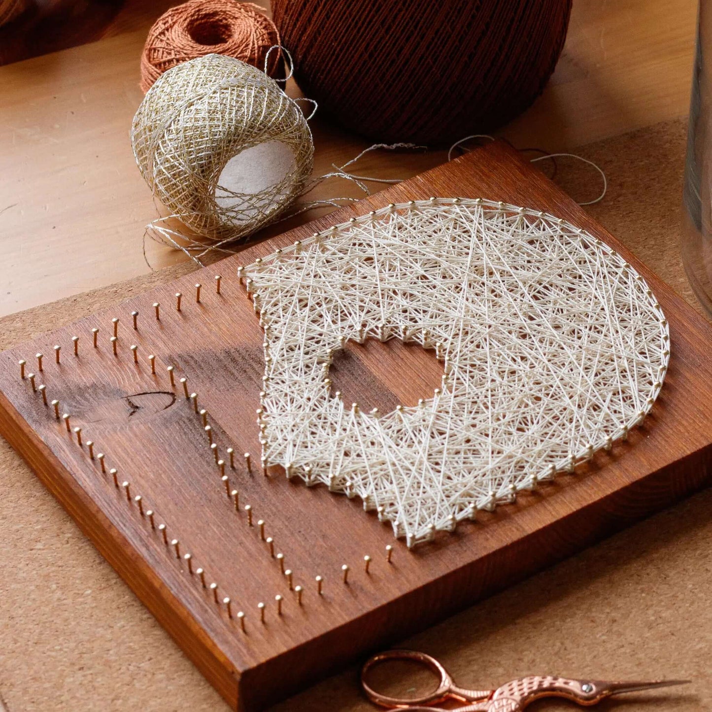 beige mountain string art sign on a brown wood base being made