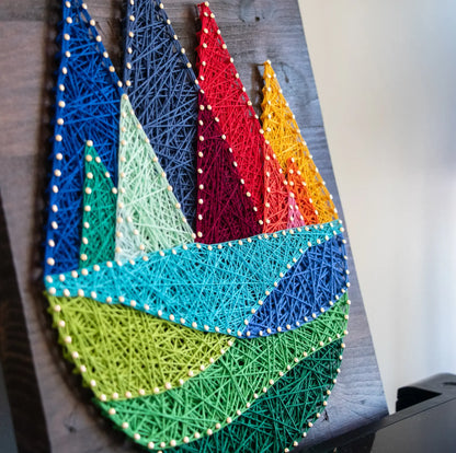 Side angle view of a colorful mountain string art project showcasing intricate threading and detailed peaks in a rainbow palette.
