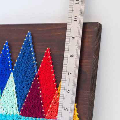 Close-up view of a finished mountain range string art pattern measured with a ruler, highlighting its detailed design and vibrant colors.