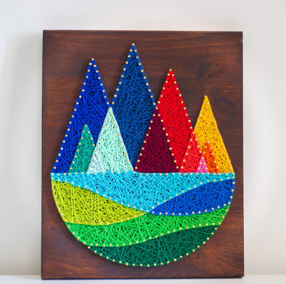 Completed mountain string art template featuring vibrant rainbow-colored peaks on a dark wooden background, perfect for DIY decor.