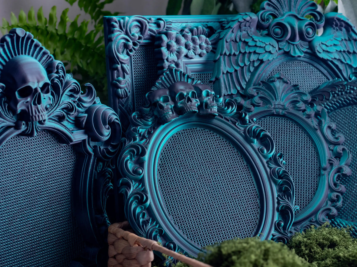 Group of gothic 3D printed cross stitch frames in Nightshade, skull and angel wing shapes on moss.